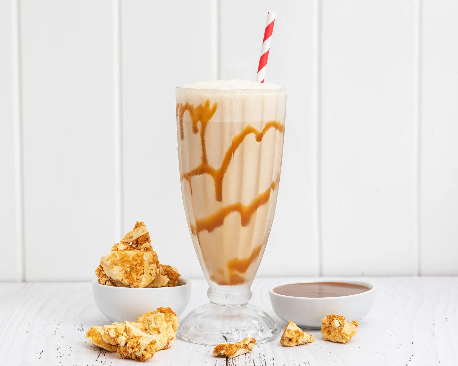 A thick milkshake with honeycomb and a striped straw